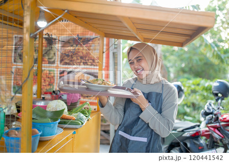 A Smiling Woman at a Food Stall Surrounded by Fresh Ingredients Under a Canopy 120441542