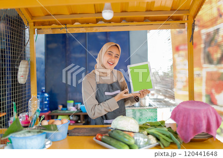 A Fresh Produce Vendor with a Smile at Their Market Stall Holding a Green Blank Sign 120441648