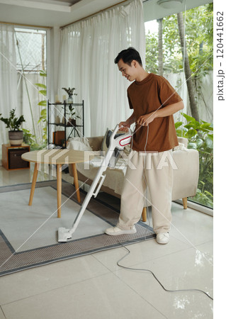 Man Vacuuming Carpet in Bright Living Room Man Vacuuming Carpet in Bright Living Room 120441662