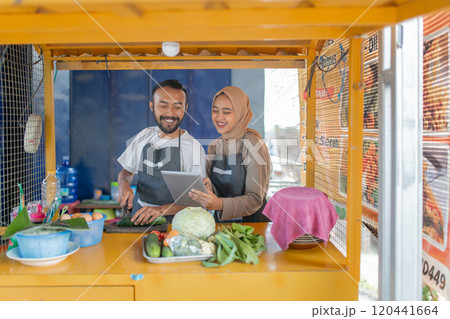 A couple runs a vibrant food stall, showcasing their culinary skills and community spirit 120441664