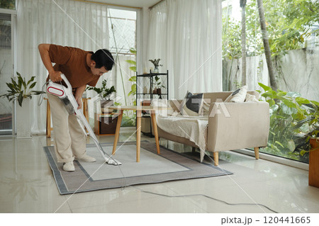 Vacuuming Living Room With Modern Cordless Vacuum Cleaner Vacuuming Living Room With Modern Cordless Vacuum Cleaner 120441665