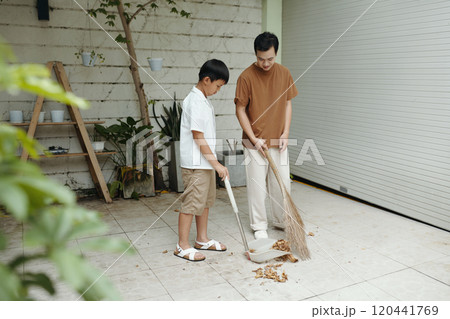 Teaching Boy Sweeping Skills in Outdoor Garage Area 120441769