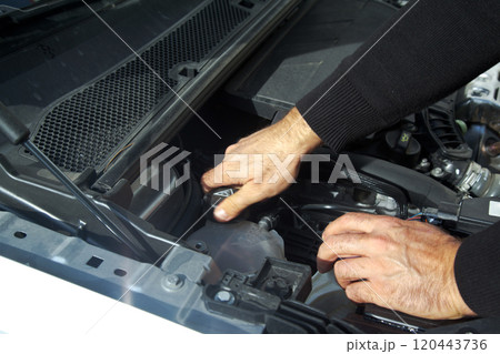 Hands of a Caucasian car mechanic performing a general check of the car's engine compartment 120443736