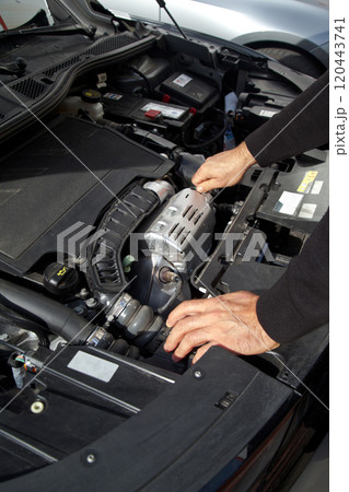 Hands of a Caucasian car mechanic performing a general check of the car's engine compartment Hands of a Caucasian car mechanic performing a general check of the car's engine compartment 120443741