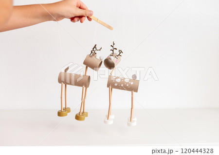 controlling DIY reindeer puppets made from cardboard tubes and bottle caps. Christmas and winter holiday craft concept. recycle paper, 120444328