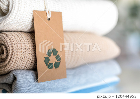 Knitted warm clothes neatly folded heap with craft tag recycling material circle arrow closeup 120444955