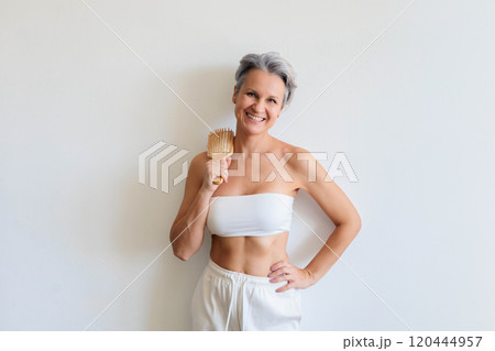 Beautiful gray haired mature woman making hairstyle haircomb posing isolated on white background Beautiful gray haired mature woman making hairstyle haircomb posing isolated on white background 120444957