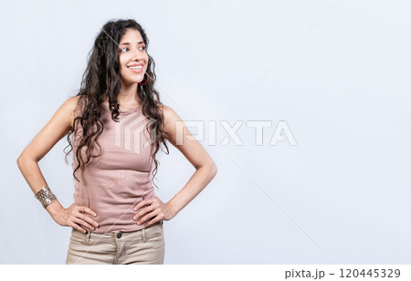 Thoughtful smiling girl looking at a blank space. Young woman looking at an advertisement to the side, Smiling girl with hands on waist looking at an advertisement Thoughtful smiling girl looking at a blank space. Young woman looking at an advertisement to the side, Smiling girl with hands on waist looking at an advertisement 120445329