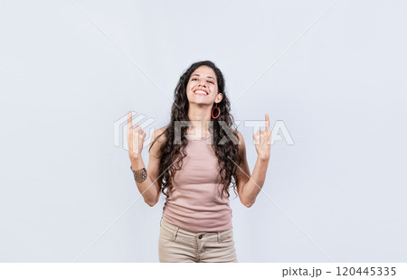 Young girl pointing an advertisement with fingers up. Smiling woman pointing with both fingers up isolated. People recommending with fingers up 120445335