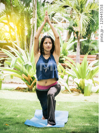 Woman doing yoga on the grass, A girl performing flexibility yoga, young girl showing yoga styles outdoors, yoga and fitness concept 120445358