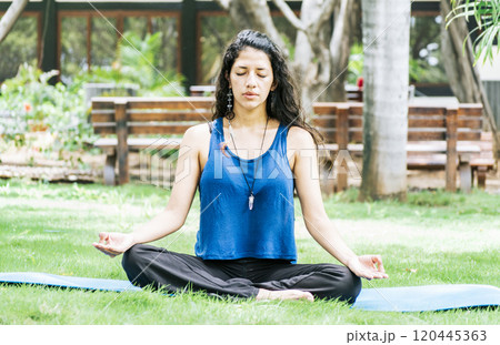 A girl sitting doing meditation yoga outdoors, Woman doing yoga outdoors, a young woman doing yoga with closed eyes. A girl sitting doing meditation yoga outdoors, Woman doing yoga outdoors, a young woman doing yoga with closed eyes. 120445363