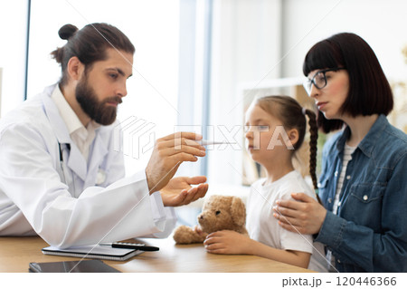 Doctor taking temperature of young girl in medical office 120446366