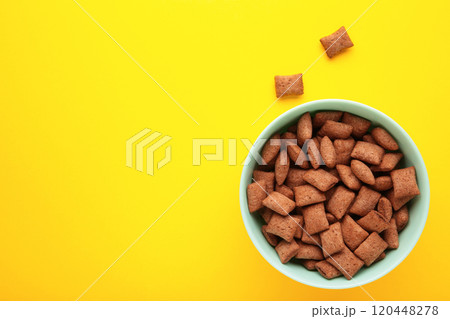 Bowl with chocolate pads on yellow background. Bowl with chocolate pads on yellow background. 120448278