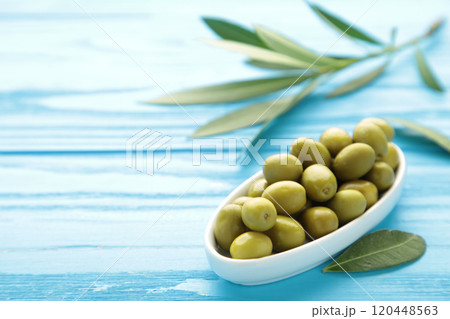 Fresh olives in bowl with leaves on blue background with copy space. 120448563