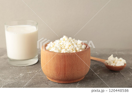 Cottage cheese for breakfast in wooden bowl with milk on grey background. Cottage cheese for breakfast in wooden bowl with milk on grey background. 120448586