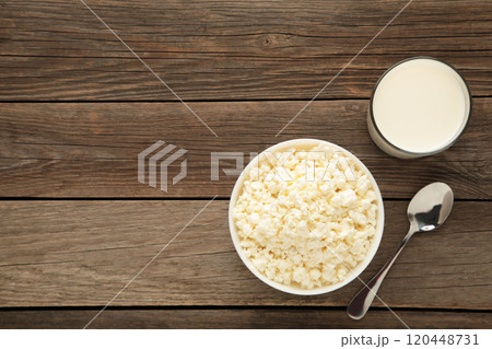 Cottage cheese for breakfast in bowl with milk on grey wooden background. 120448731