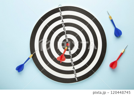 Dart board with red darts on blue background. 120448745