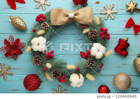 Wreath from fir, pine and spruce twigs, decorated with cotton, flowers ad christmas decoration on blue wooden background 120448840