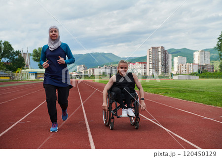 A Muslim woman in a burqa running together with a woman in a wheelchair on the marathon course, preparing for future competitions. 120450129