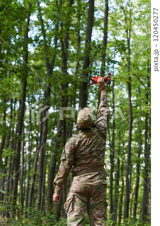 Elite military unit, equipped with state-of-the-art technology including a drone, strategically navigates and surveys dangerous wooded terrain, showcasing their precision, cooperation, and specialized Elite military unit, equipped with state-of-the-art technology including a drone, strategically navigates and surveys dangerous wooded terrain, showcasing their precision, cooperation, and specialized 120450277