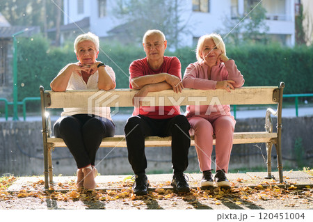 A group of elderly individuals, including a senior man and two older women, sits in a park on a sunny autumn day, embodying the concept of healthy aging through companionship, relaxation, and outdoor A group of elderly individuals, including a senior man and two older women, sits in a park on a sunny autumn day, embodying the concept of healthy aging through companionship, relaxation, and outdoor 120451004