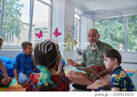 Reading time in an elementary school or kindergarten, a teacher reading a book to children in an elementary school or kindergarten. The concept of pre-school education. Selective focus 120451024