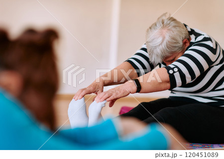 Senior Woman Practicing Back Stretches in a Sunlit Space for Optimal Health and Well Being Senior Woman Practicing Back Stretches in a Sunlit Space for Optimal Health and Well Being 120451089