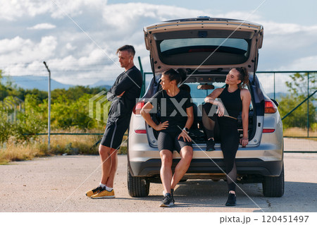 Morning Prep Team of Athletes Gearing Up for Run Beside Car. Morning Prep Team of Athletes Gearing Up for Run Beside Car. 120451497