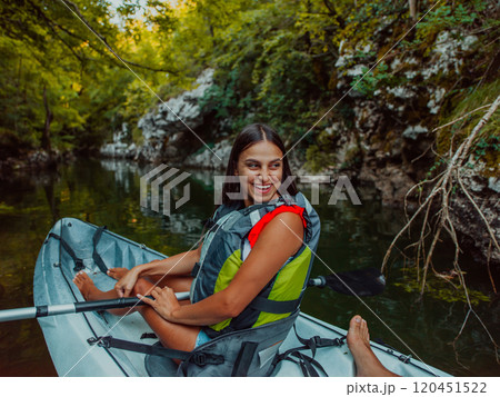 A smiling woman enjoying a relaxing kayak ride with a friend while exploring river canyons 120451522