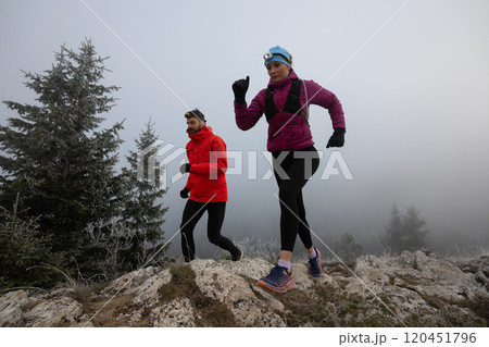 trail running couple man and woman running on a mountain path 120451796