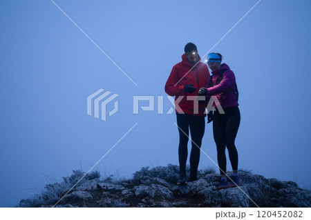 Runners tired of breathing after training look at their tech sports smart watch in night on maintain  120452082