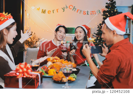 Group of young Asian man and women as friends having fun at a New Year's celebration, holding gift boxes standing by Christmas tree decoration, midnight countdown Party at home with holiday season. Group of young Asian man and women as friends having fun at a New Year's celebration, holding gift boxes standing by Christmas tree decoration, midnight countdown Party at home with holiday season. 120452108