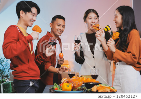 Group of young Asian man and women as friends having fun at a New Year's celebration, holding gift boxes standing by Christmas tree decoration, midnight countdown Party at home with holiday season. Group of young Asian man and women as friends having fun at a New Year's celebration, holding gift boxes standing by Christmas tree decoration, midnight countdown Party at home with holiday season. 120452127