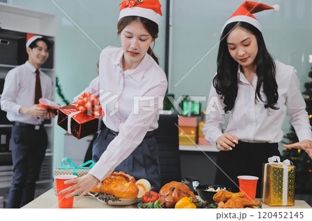 full length view of a group of business team wearing red Santa hat and exchange gift box together in the office for Christmas. full length view of a group of business team wearing red Santa hat and exchange gift box together in the office for Christmas. 120452145