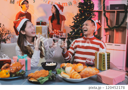 Group of happy Asian friends celebrating Christmas and decorate the Christmas tree indoors. Beauty woman with Christmas Gifts. New Year party. Woman hands decorate Christmas tree red ball, bauble. 120452178