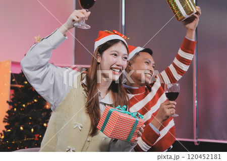 Group of happy Asian friends celebrating Christmas and decorate the Christmas tree indoors. Beauty woman with Christmas Gifts. New Year party. Woman hands decorate Christmas tree red ball, bauble. Group of happy Asian friends celebrating Christmas and decorate the Christmas tree indoors. Beauty woman with Christmas Gifts. New Year party. Woman hands decorate Christmas tree red ball, bauble. 120452181