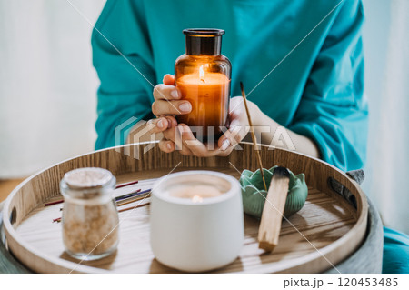 Young woman practicing self-care with aromatherapy and candles in a peaceful indoor setting. Relaxation and mindfulness concept. Young woman practicing self-care with aromatherapy and candles in a peaceful indoor setting. Relaxation and mindfulness concept. 120453485