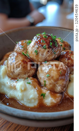 Savory meatballs served over creamy mashed potatoes with rich sauce and nuts 120454639