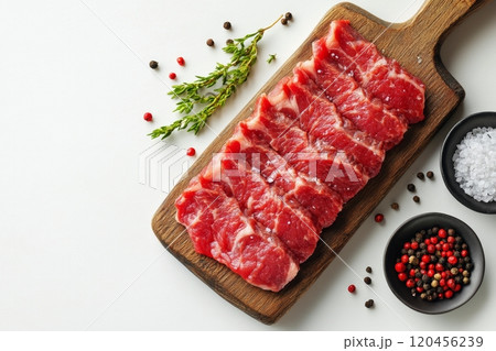 Fresh marbled beef steaks arranged on a wooden cutting board with herbs and salt 120456239