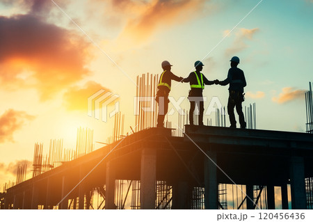 Silhouette of a construction worker working on top of a building at sunset. 120456436