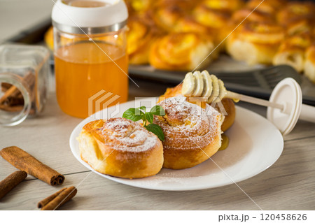 Pastries. Sweet buns with cottage cheese filling and honey in a plate on a wooden table 120458626