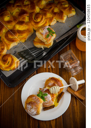 Pastries. Sweet buns with cottage cheese filling and honey in a plate on a wooden table 120458635