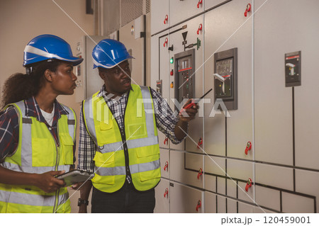 Electrical engineer team are working in control room. Electrical engineer man checking Power Distribution Cabinet in the control room 120459001