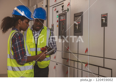 Electrical engineer team are working in control room. Electrical engineer man checking Power Distribution Cabinet in the control room Electrical engineer team are working in control room. Electrical engineer man checking Power Distribution Cabinet in the control room 120459002