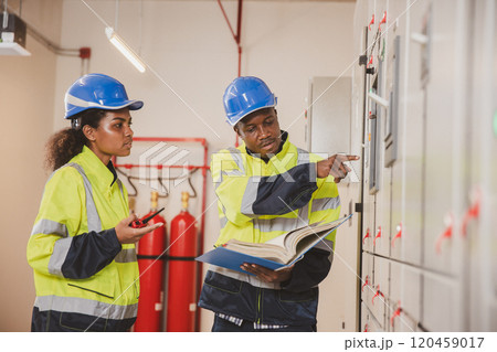 Electrical engineer team are working in control room. Electrical engineer man checking Power Distribution Cabinet in the control room Electrical engineer team are working in control room. Electrical engineer man checking Power Distribution Cabinet in the control room 120459017