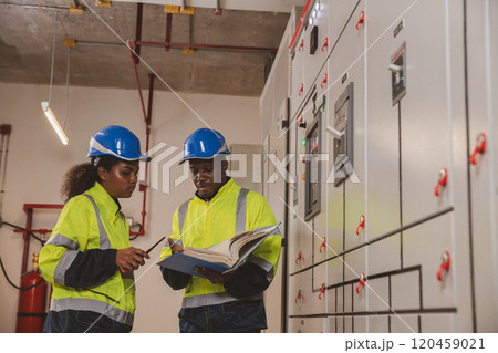 Electrical engineer team are working in control room. Electrical engineer man checking Power Distribution Cabinet in the control room 120459021