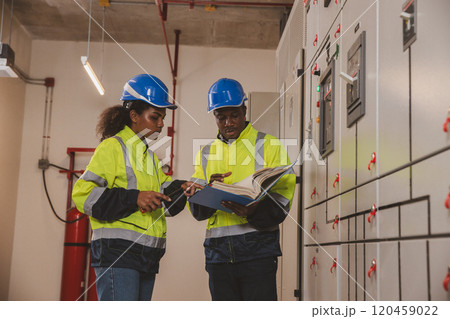 Electrical engineer team are working in control room. Electrical engineer man checking Power Distribution Cabinet in the control room Electrical engineer team are working in control room. Electrical engineer man checking Power Distribution Cabinet in the control room 120459022