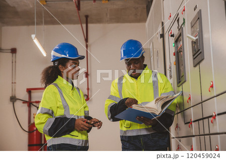 Electrical engineer team are working in control room. Electrical engineer man checking Power Distribution Cabinet in the control room Electrical engineer team are working in control room. Electrical engineer man checking Power Distribution Cabinet in the control room 120459024