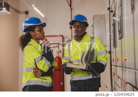 Electrical engineer team are working in control room. Electrical engineer man checking Power Distribution Cabinet in the control room Electrical engineer team are working in control room. Electrical engineer man checking Power Distribution Cabinet in the control room 120459025