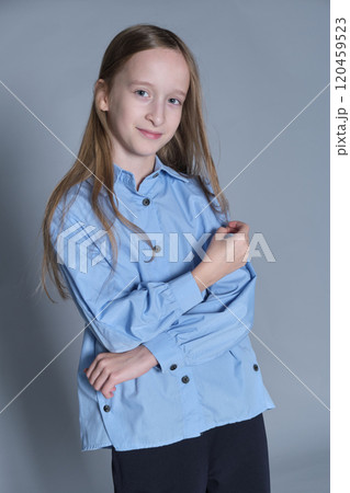 Confident young girl stands with arms crossed, wearing a smart blue shirt and black trousers, a blend of attitude and style. Confident young girl stands with arms crossed, wearing a smart blue shirt and black trousers, a blend of attitude and style. 120459523